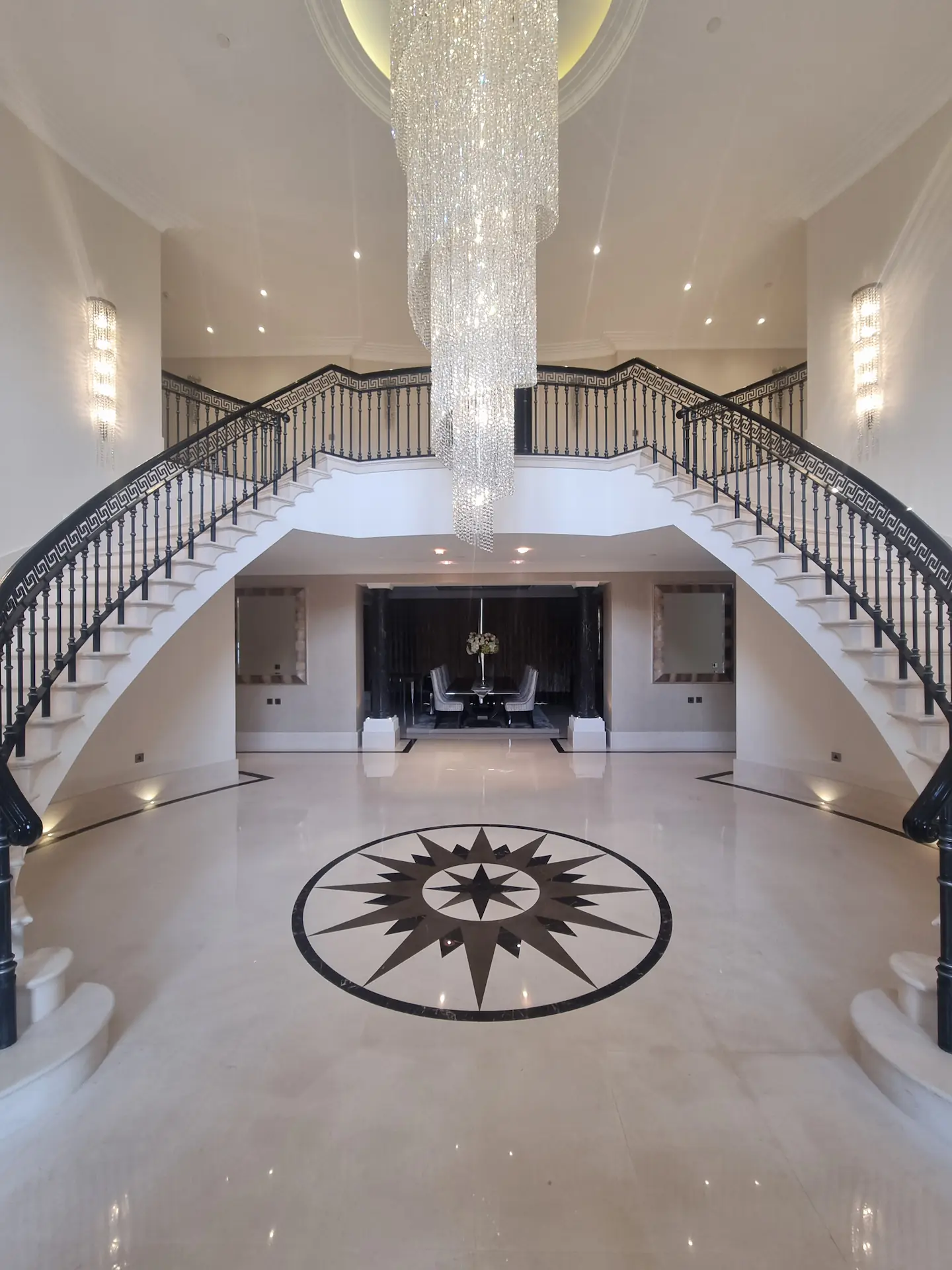 Polished marble entrance floor with a dark inlaid compass medallion beneath a double staircase