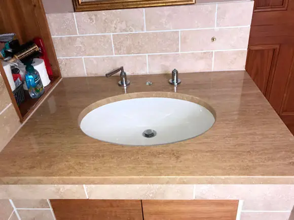 Stone vanity top with a white inset basin and wall-mounted taps