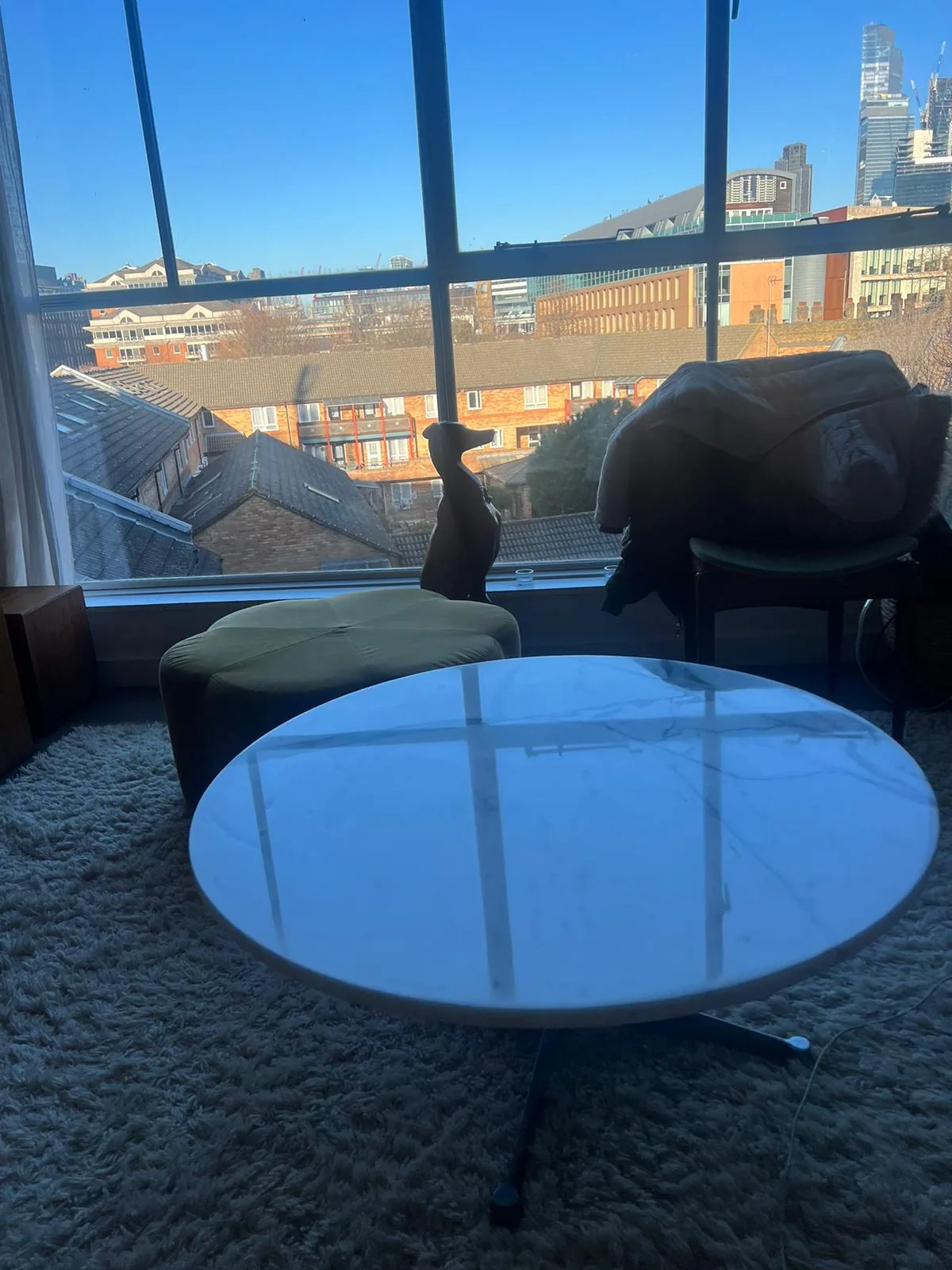 Light circular tabletop reflecting blue daylight beside large windows