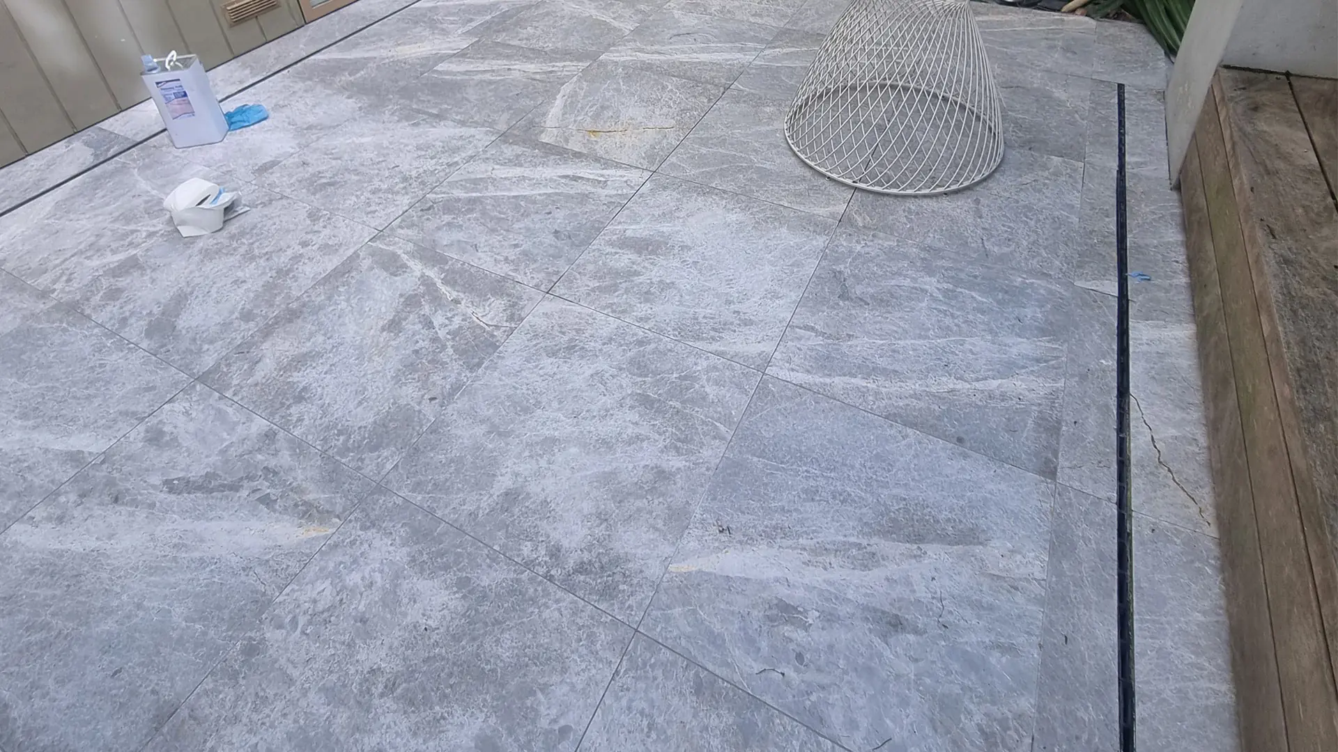 Stone terrace floor part way through restoration, with cleaning materials in place on the surface