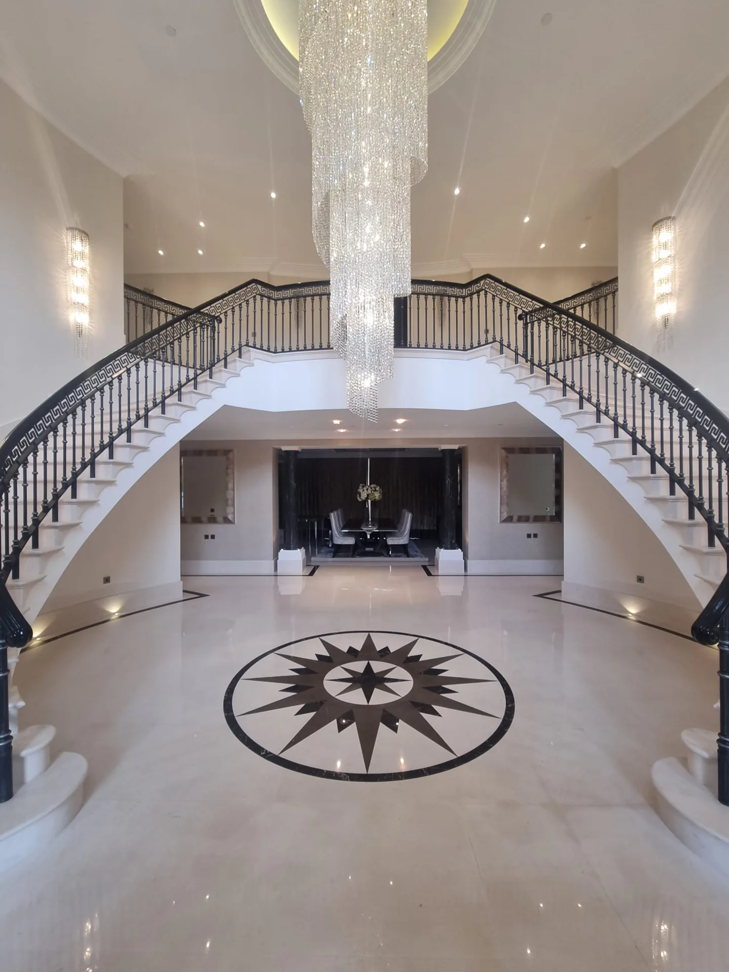 Tall view of an entrance floor with a compass medallion and chandelier