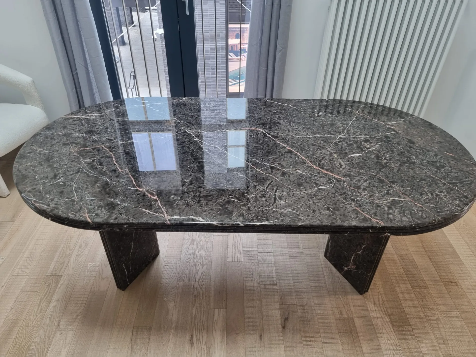 Patterned oval stone table beside glazed doors and a radiator