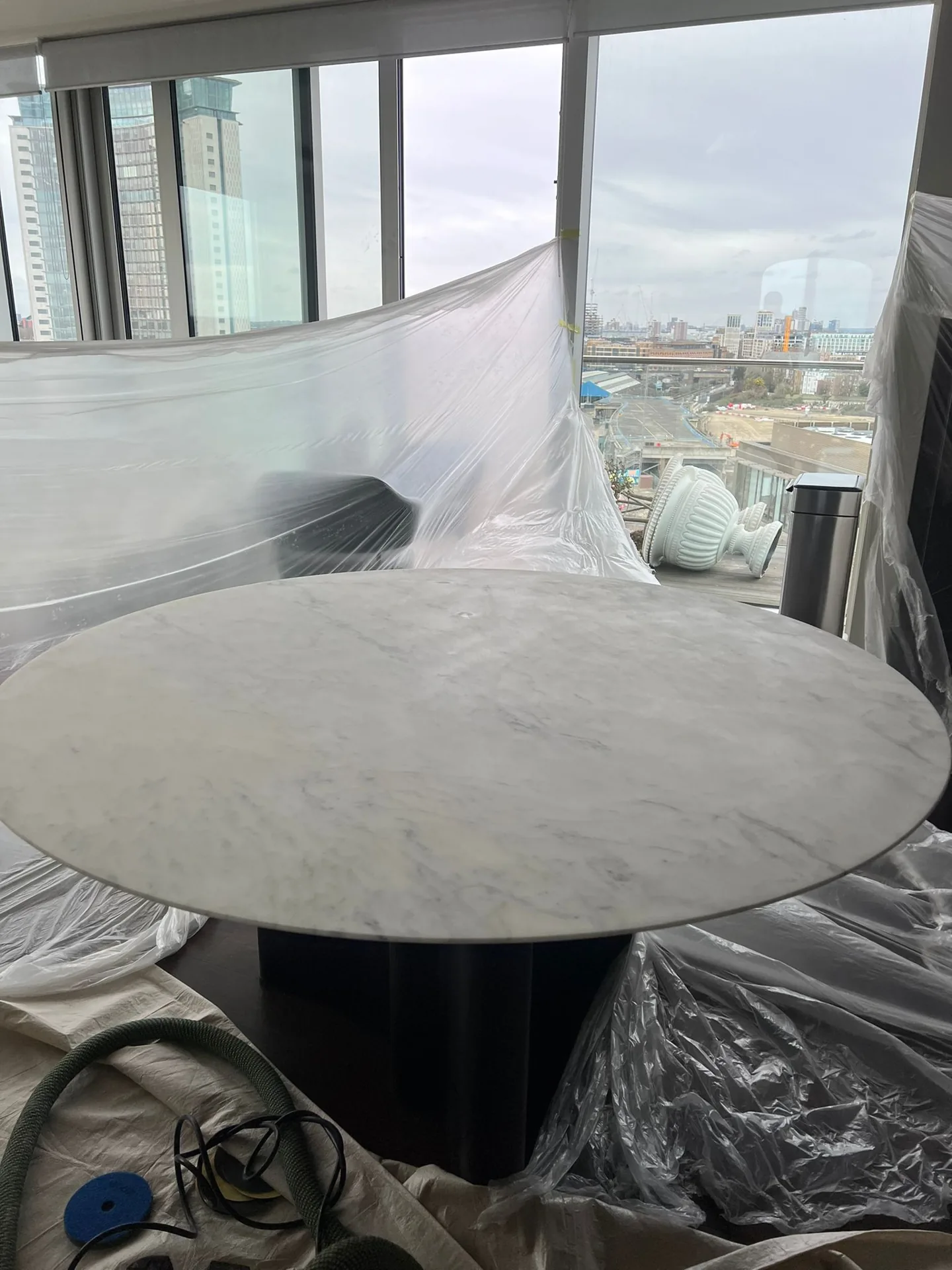 Round veined stone table surrounded by protective sheeting