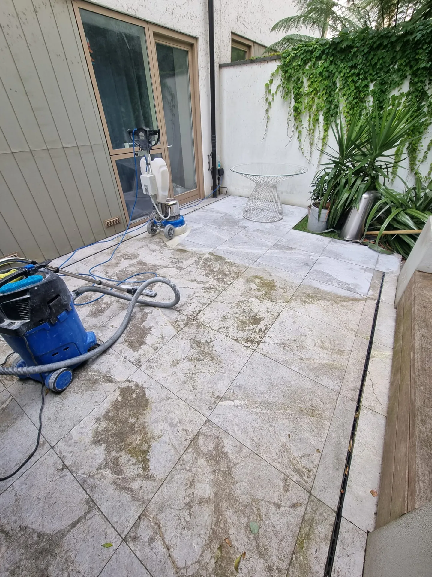 Terrace paving with equipment, hoses and darker damp areas