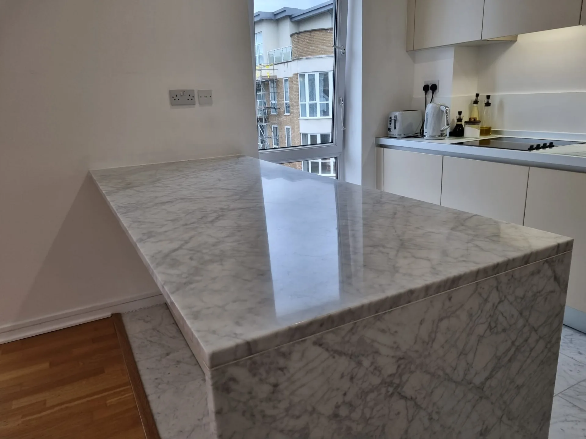 Veined waterfall island worktop in a light kitchen