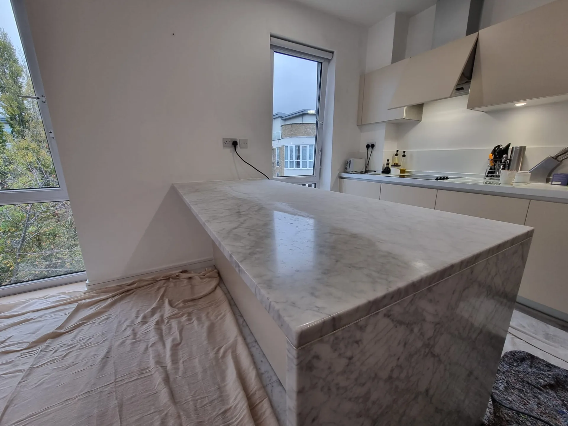 Waterfall worktop beside cabinetry, with protective covering nearby